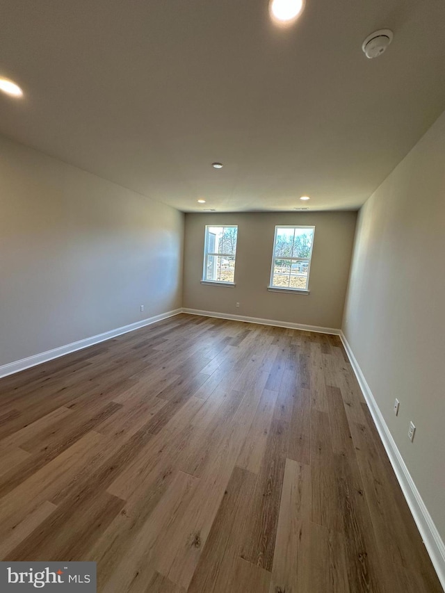 unfurnished room featuring baseboards, wood finished floors, and recessed lighting