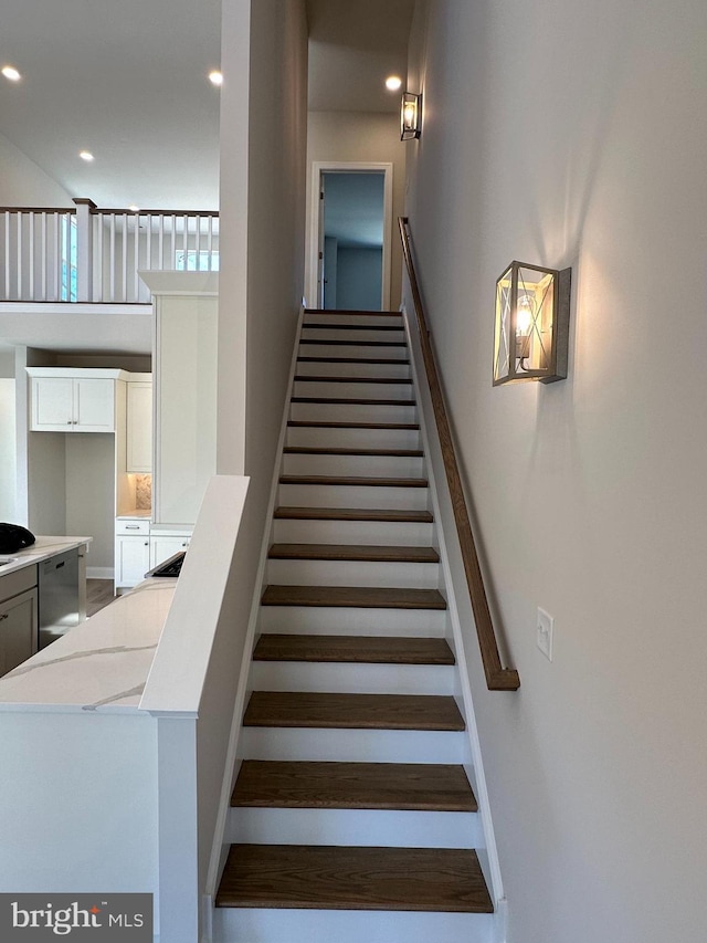 stairs featuring a towering ceiling, baseboards, and recessed lighting