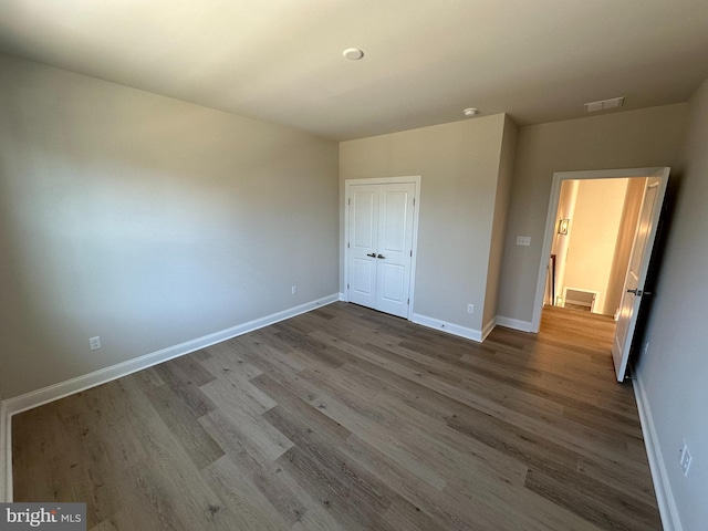 unfurnished bedroom featuring a closet, wood finished floors, visible vents, and baseboards