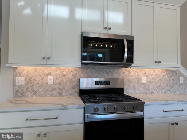 kitchen with stainless steel appliances, light stone countertops, white cabinets, and decorative backsplash