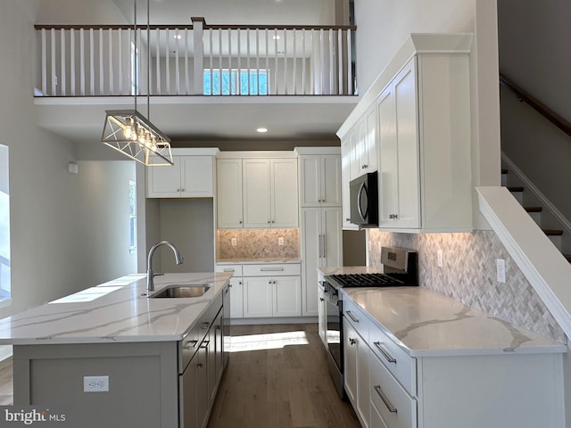 kitchen with white cabinets, a towering ceiling, dark wood-type flooring, stainless steel appliances, and a sink