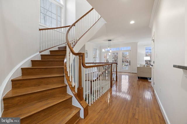 stairs with recessed lighting, a towering ceiling, ornamental molding, baseboards, and hardwood / wood-style flooring