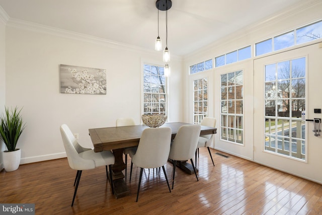 dining space featuring ornamental molding, hardwood / wood-style floors, visible vents, and baseboards