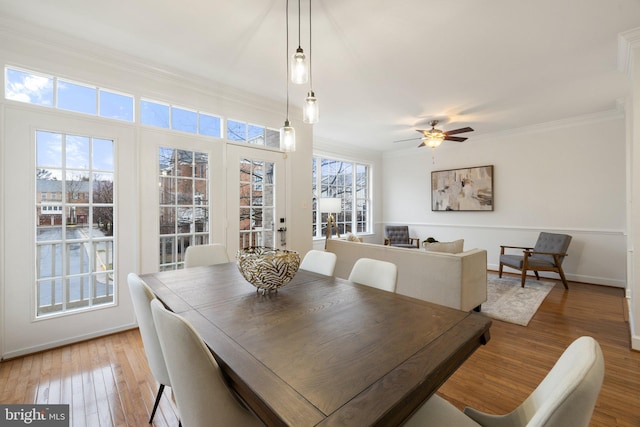 dining room with light wood finished floors, baseboards, ornamental molding, and a ceiling fan