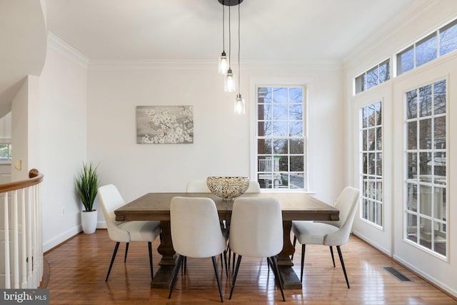 dining area with baseboards, wood-type flooring, visible vents, and crown molding