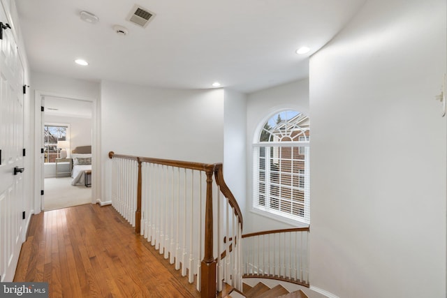 hall featuring visible vents, hardwood / wood-style flooring, an upstairs landing, and recessed lighting