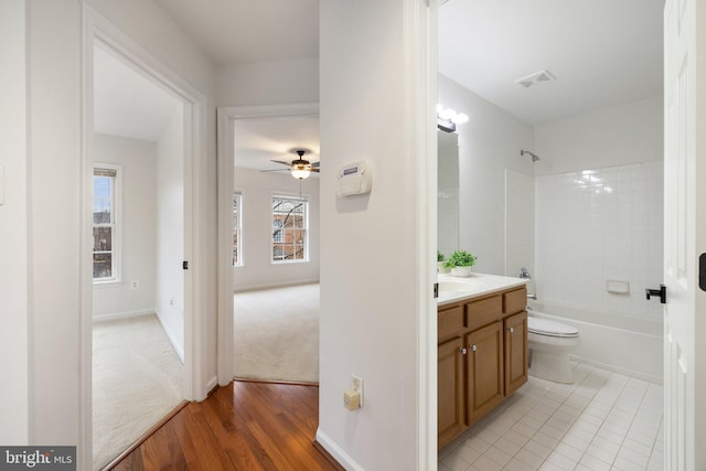 full bath featuring baseboards, visible vents, toilet,  shower combination, and vanity