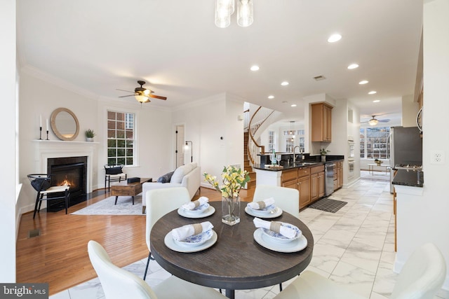 dining room featuring a fireplace with flush hearth, stairway, marble finish floor, crown molding, and recessed lighting