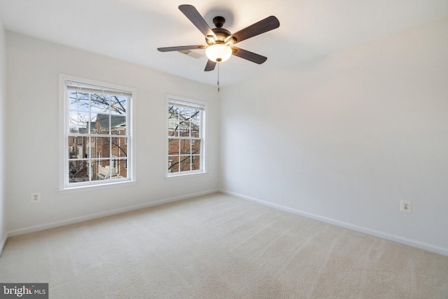 spare room with baseboards, ceiling fan, and light colored carpet