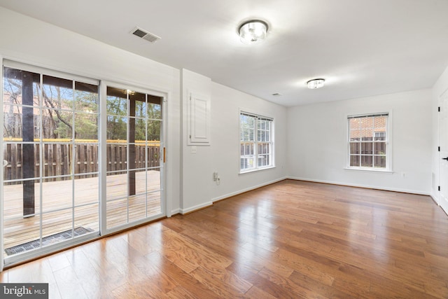 unfurnished room with visible vents, baseboards, and wood finished floors