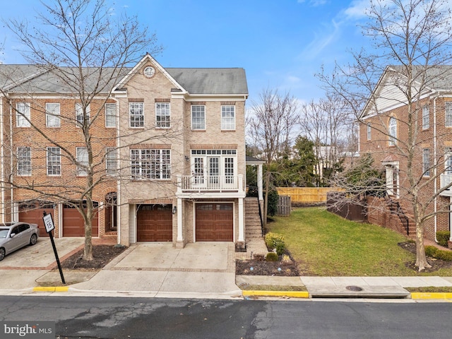 multi unit property featuring driveway, a balcony, an attached garage, fence, and a front yard