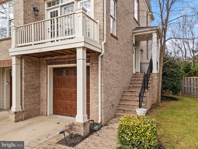 entrance to property featuring driveway, brick siding, and an attached garage