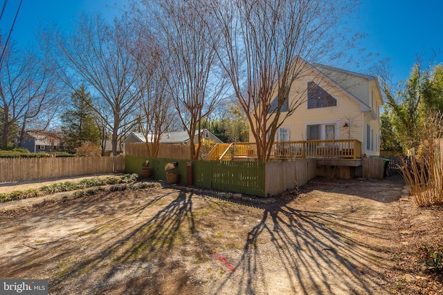 rear view of house featuring a deck and fence