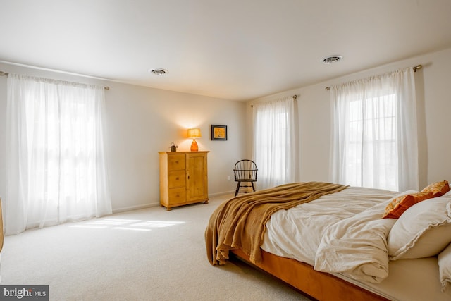 bedroom featuring visible vents, baseboards, and light colored carpet