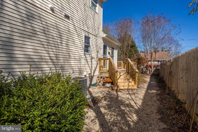 view of side of home with cooling unit, a wooden deck, and fence private yard