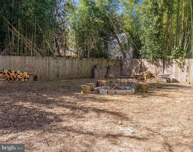 view of yard featuring an outdoor fire pit and fence