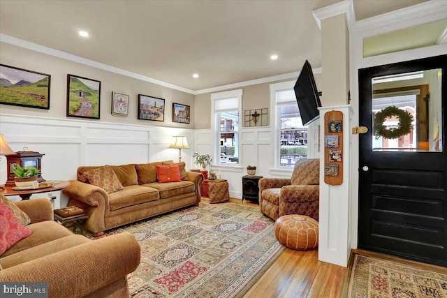 living area featuring light wood finished floors, a decorative wall, recessed lighting, and crown molding