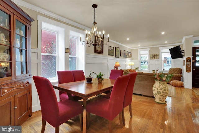 dining room featuring wainscoting, crown molding, a decorative wall, and an inviting chandelier