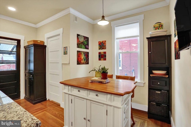 kitchen featuring ornamental molding, a healthy amount of sunlight, white cabinetry, and baseboards