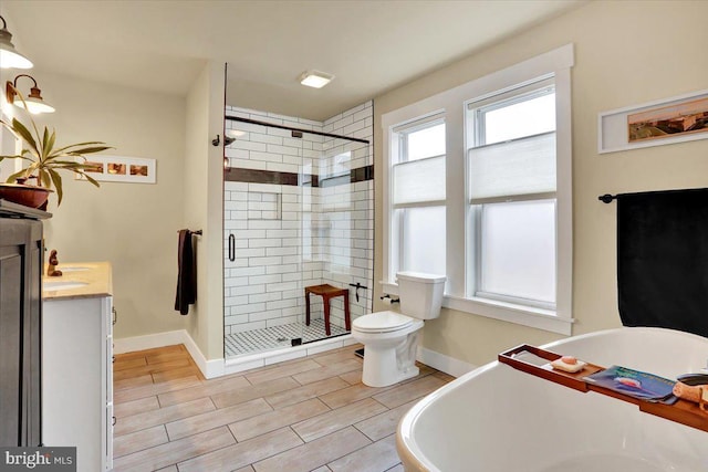 full bath with baseboards, vanity, wood finish floors, a freestanding tub, and a shower stall