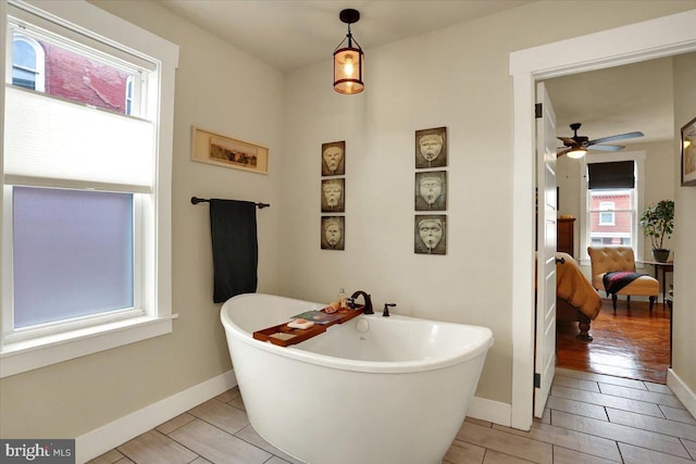 bathroom featuring a soaking tub, ceiling fan, and baseboards