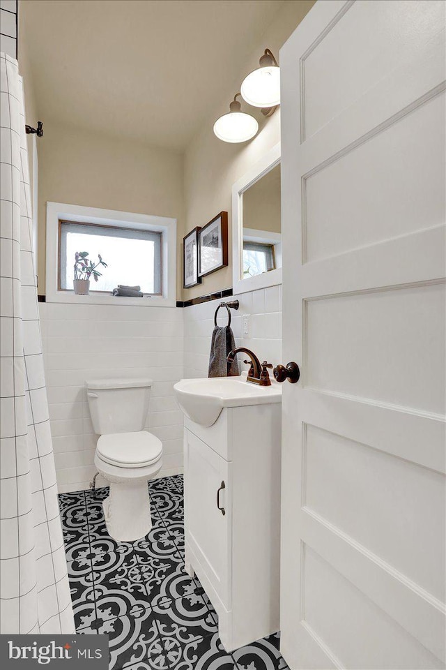 full bath featuring plenty of natural light, tile walls, toilet, and vanity