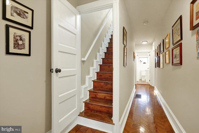 hall with visible vents, stairway, and baseboards