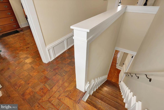 stairway with wainscoting and a decorative wall