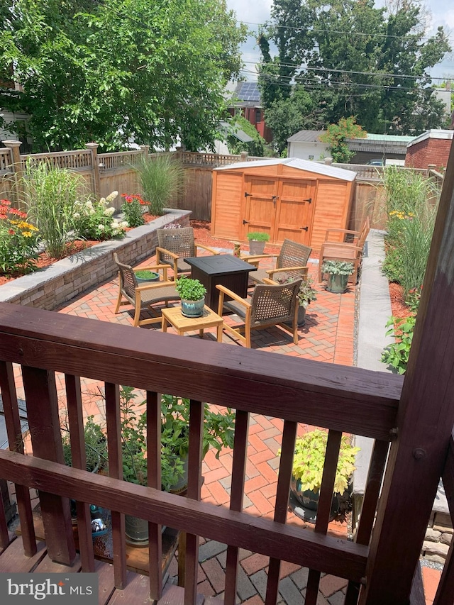 deck featuring an outbuilding, a storage shed, a patio area, a fenced backyard, and an outdoor living space