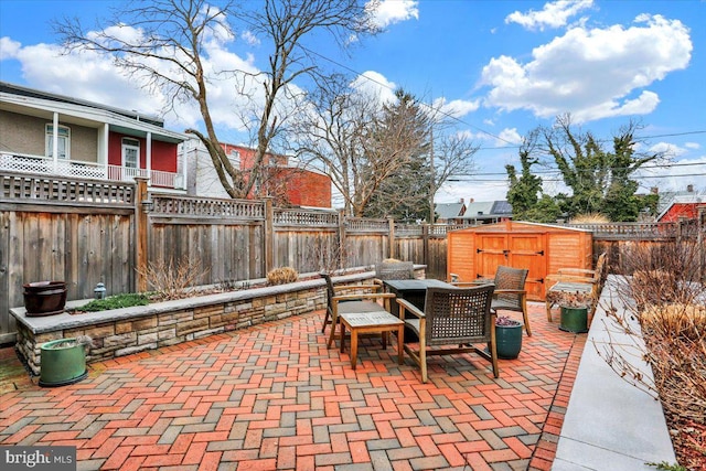 view of patio with a storage unit, an outdoor structure, and a fenced backyard