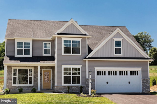 craftsman inspired home with board and batten siding, a front yard, stone siding, and aphalt driveway