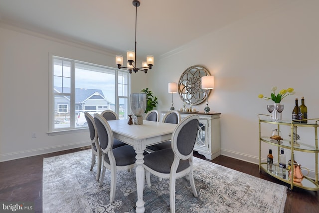 dining space with crown molding, baseboards, dark wood-type flooring, and a notable chandelier