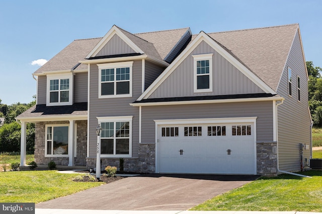 craftsman-style home with a garage, stone siding, aphalt driveway, board and batten siding, and a front yard