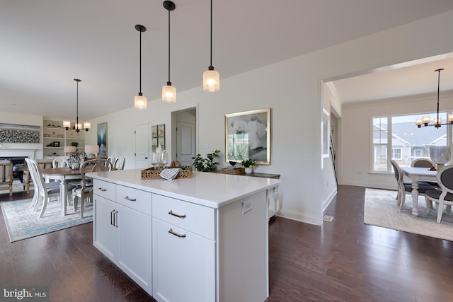 kitchen with dark wood finished floors, open floor plan, light countertops, white cabinetry, and a notable chandelier