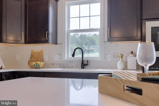 kitchen with dark brown cabinetry, light countertops, and a sink