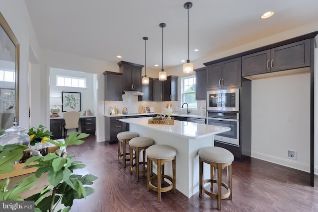 kitchen with oven, a kitchen breakfast bar, light countertops, decorative backsplash, and dark wood finished floors