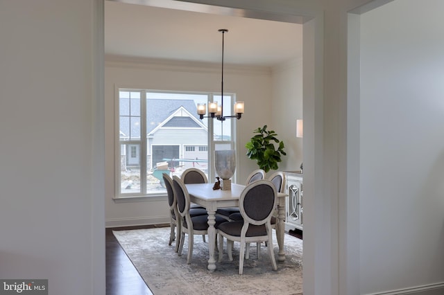 dining room featuring baseboards, crown molding, a chandelier, and wood finished floors