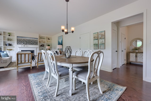 dining space featuring baseboards, dark wood-style flooring, a fireplace, and an inviting chandelier