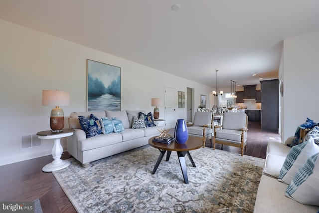 living room featuring baseboards, visible vents, a notable chandelier, and wood finished floors