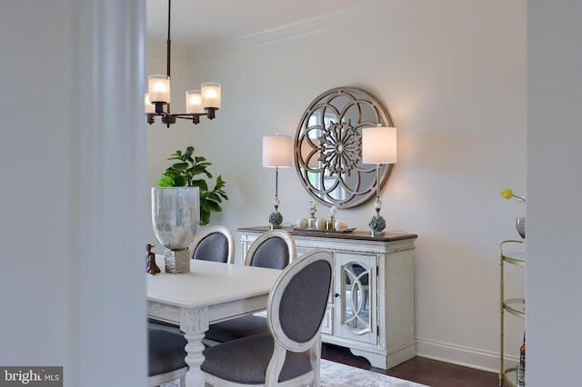 dining room with an inviting chandelier, baseboards, dark wood-style flooring, and ornamental molding