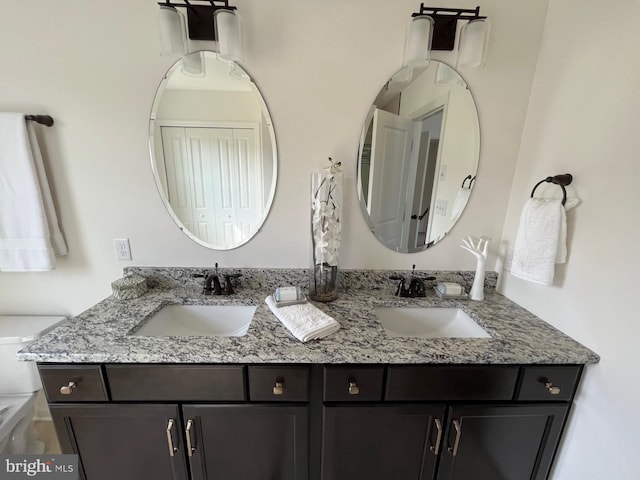 bathroom with double vanity, a sink, and toilet