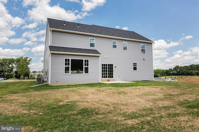 rear view of property with central air condition unit, roof with shingles, a lawn, and a patio