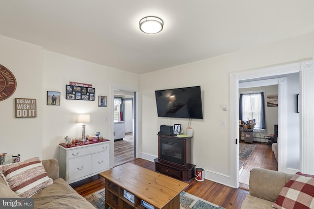 living room with dark wood-type flooring and baseboards