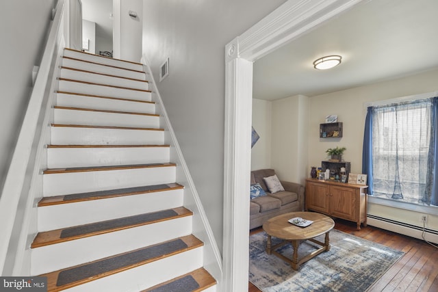 stairs featuring hardwood / wood-style floors, a baseboard radiator, and visible vents