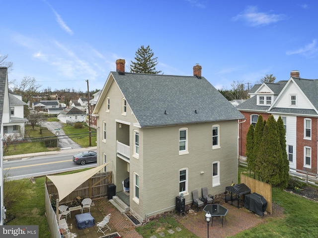 back of property with a fire pit, a shingled roof, cooling unit, and fence