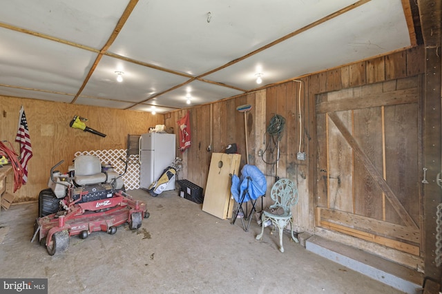 below grade area featuring a garage, freestanding refrigerator, and wooden walls