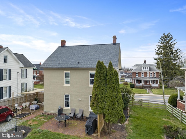 rear view of house with an outdoor fire pit, a fenced backyard, a yard, roof with shingles, and a patio area