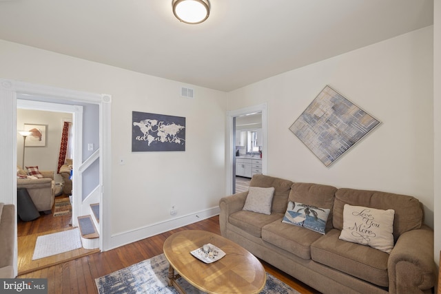 living room featuring hardwood / wood-style flooring, baseboards, and visible vents