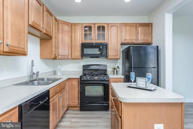 kitchen with black appliances, light countertops, light wood-type flooring, and a sink