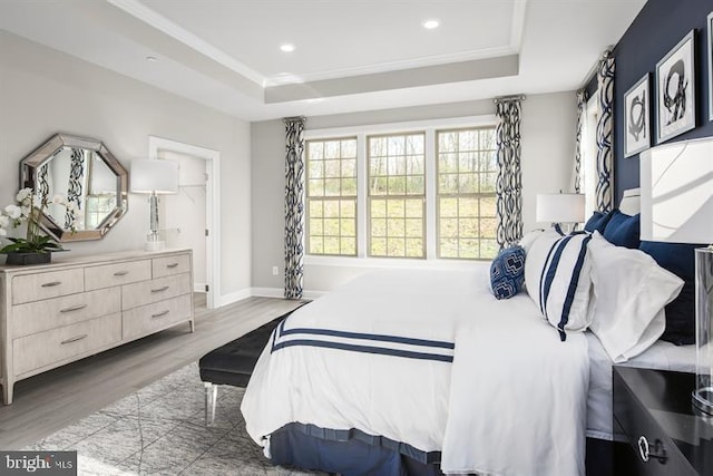 bedroom with baseboards, a tray ceiling, wood finished floors, and recessed lighting